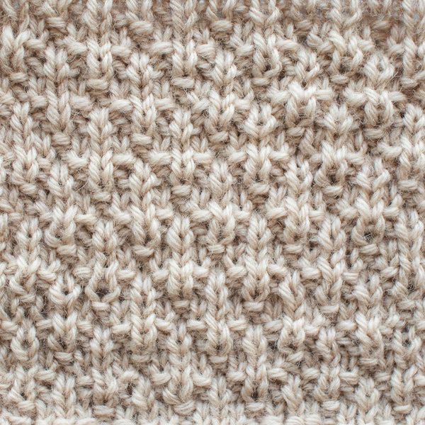 Close-up of a knitted seersucker stitch swatch showing alternating raised and recessed vertical texture created by knit and purl stitches.